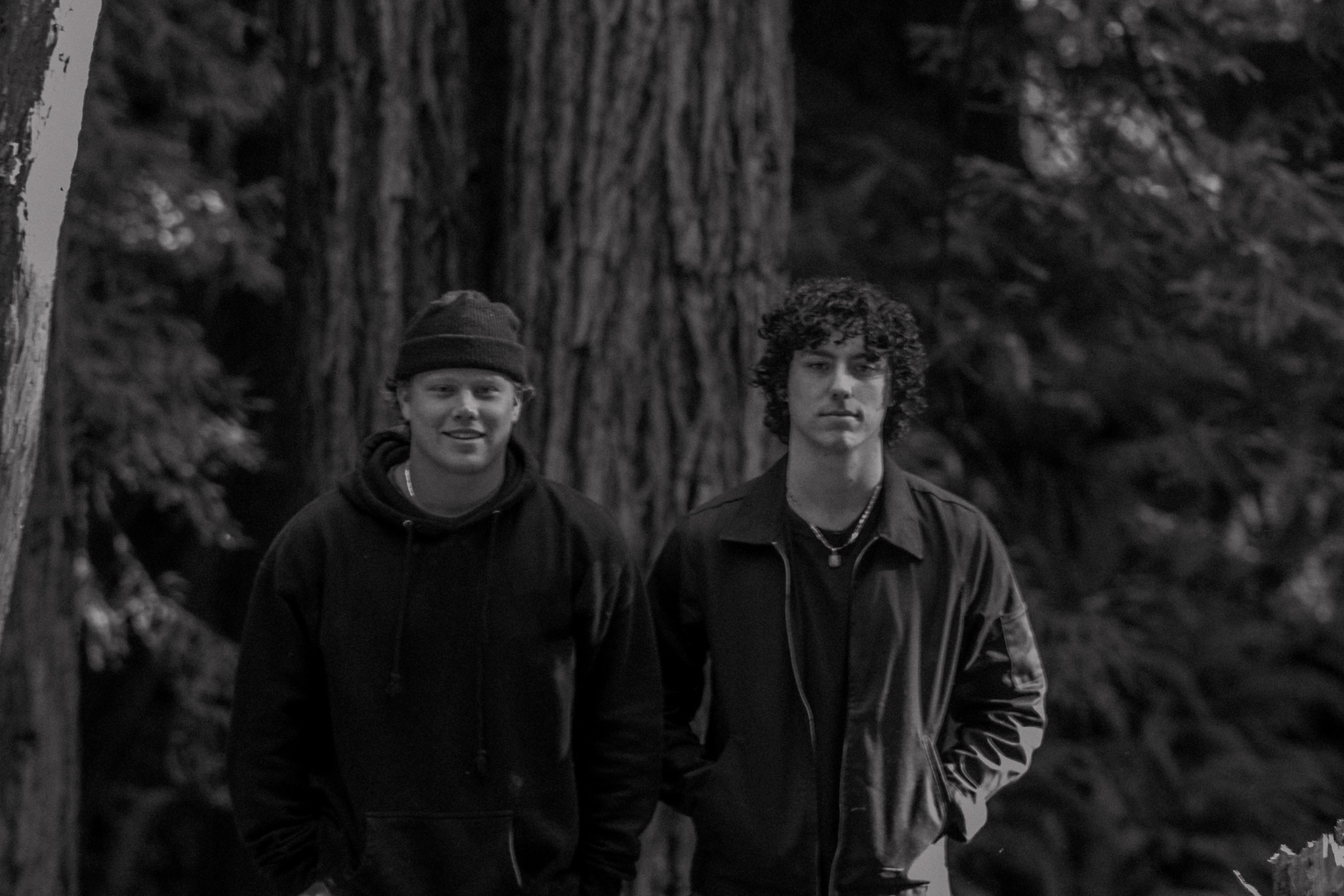 A black and white photo of two people standing in a forest